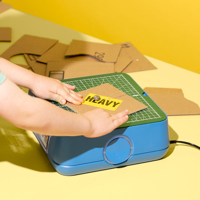 Young maker cutting a cardboard piece with the ChompSaw kids power tool.