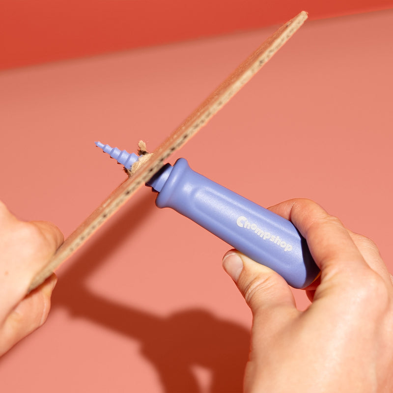 Person demonstrating Chompshop's hole punch tool twisting through cardboard.