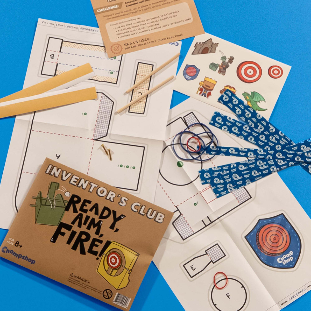 Chompshop Inventor's Club monthly project pack with printed templates, wooden rods, and double-sided tape for building a cardboard project.