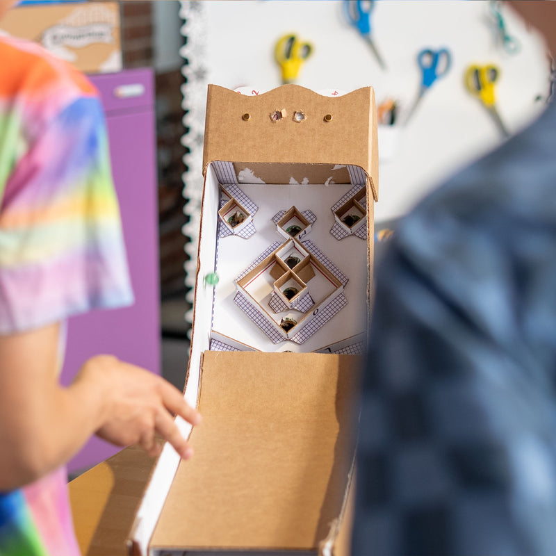 Two kids playing skee-ball with Chompshop's Ramp & Roll cardboard project