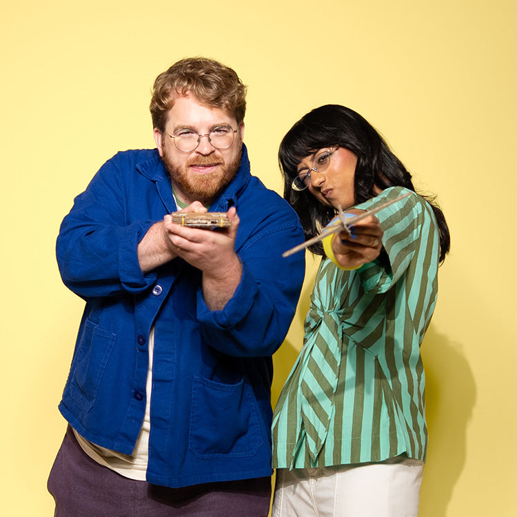 Founders of Chompshop, Kausi Raman and Max Liechty posing for a picture with cardboard props made by the ChompSaw. 