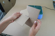 Two pieces of cardboard being slotted together along a cut line, to demonstrate that the width of cardboard cut is perfect for creating sturdy slots and tabs. ChompSaw by ChompShop in the background.