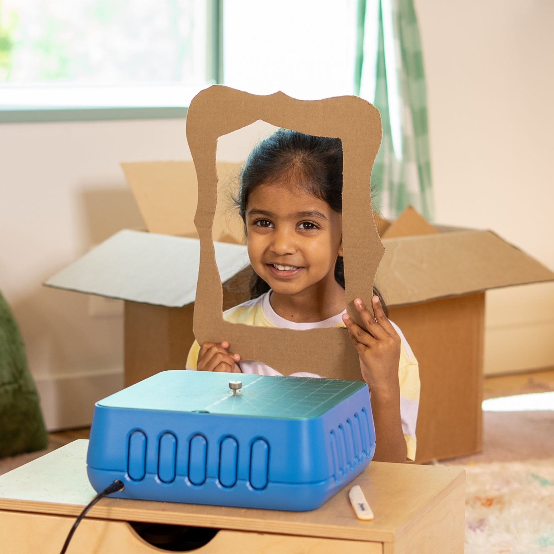 Young maker holding a decorative cardboard picture frame she built with the ChompSaw kids power tool.
