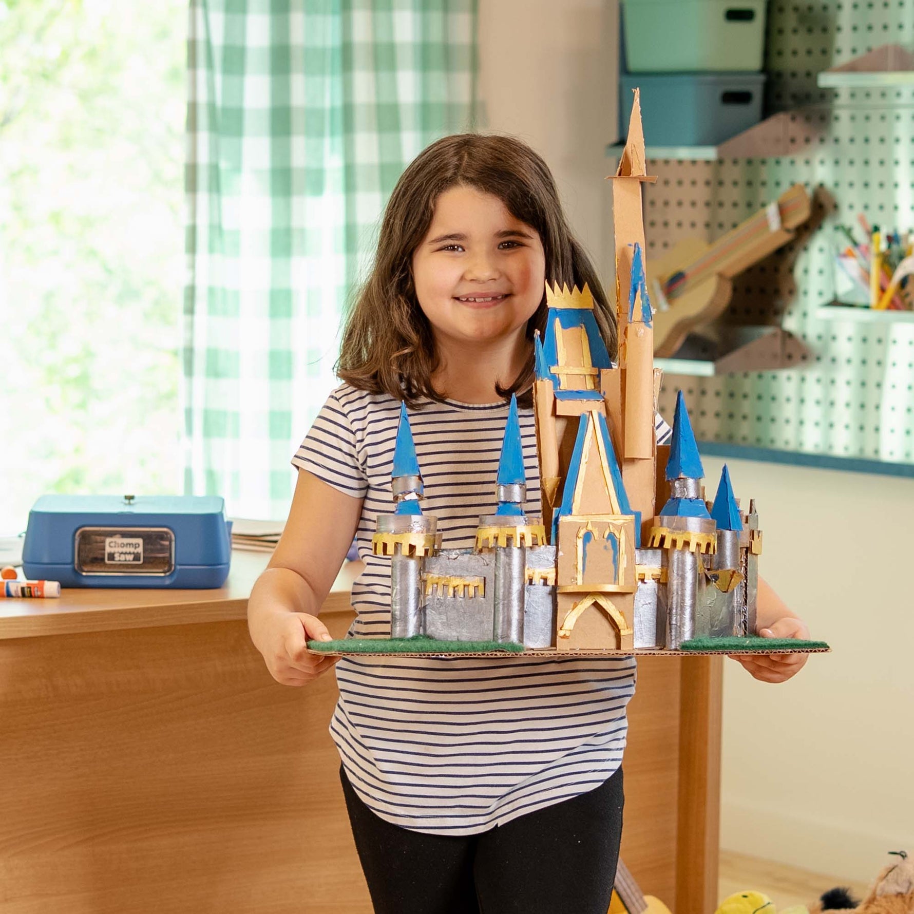 Young maker holding a decorative cardboard castle built with the ChompSaw.
