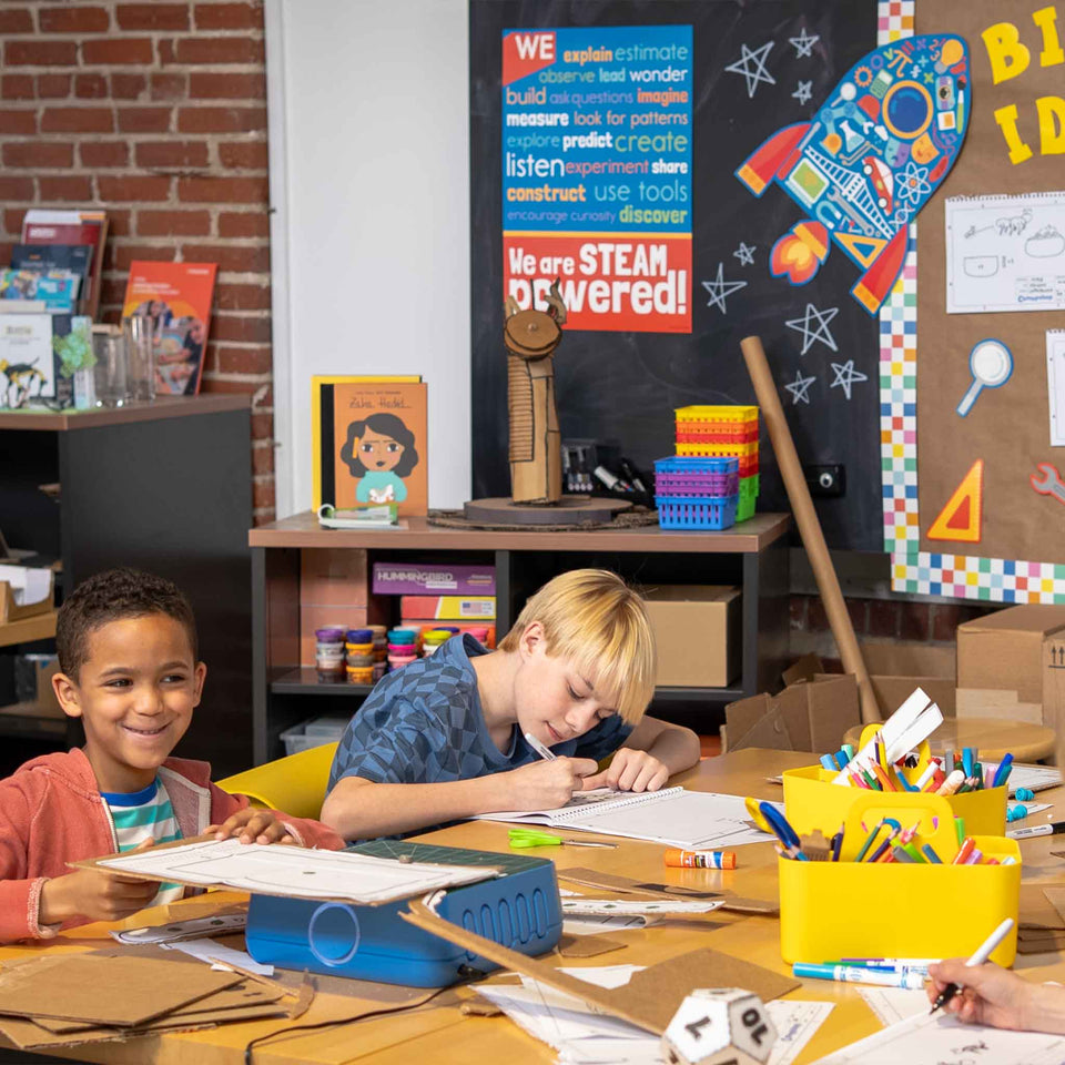 Children in a classroom setting with educational materials and a colorful rocket model on the wall.
