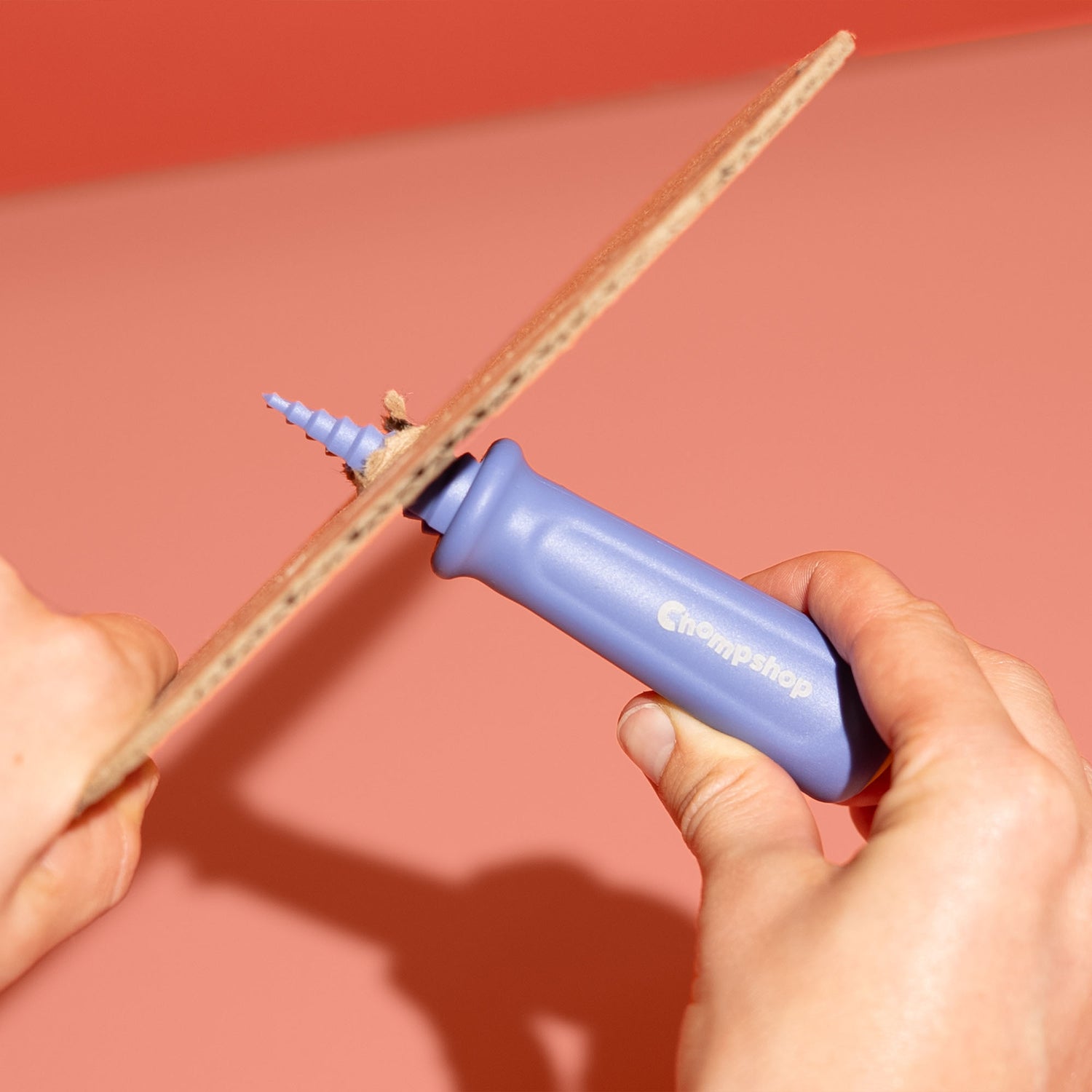 Person demonstrating Chompshop's hole punch tool twisting through cardboard.