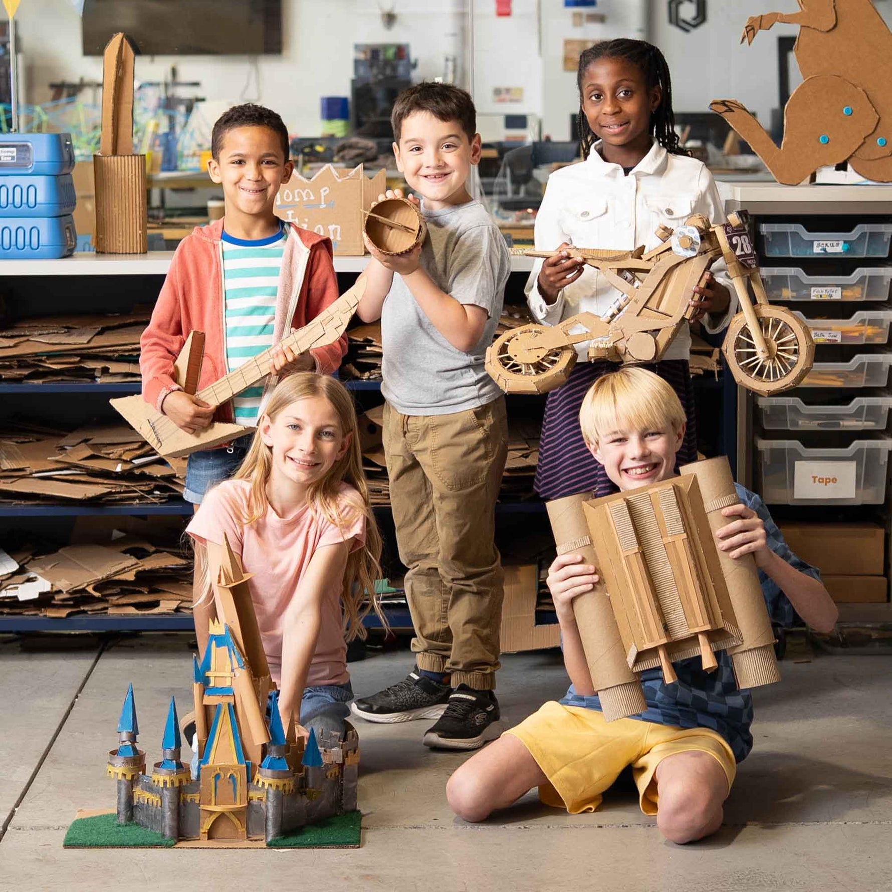Kids holding a variety of cardboard projects made with the ChompSaw.