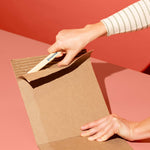 Chompshop Scoring Tool accessory being used to remove the top layer of a cardboard sheet.